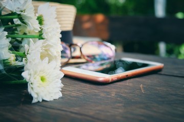 Fototapeta premium Blurry and soft focus Bouquet of white flowers and mobile phone on wooden background.