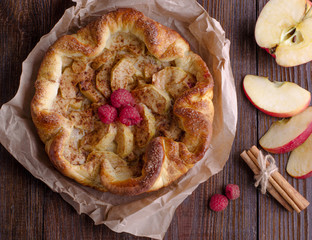 apple pie with cinnamon and raspberry on a wooden table