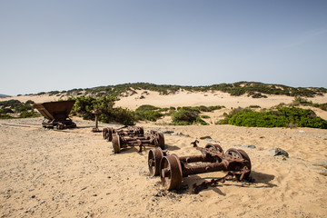 Dilapidated rail track and wagon of mining industry in desert of sardinia.