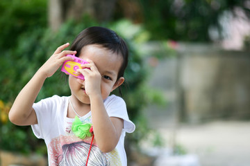 Cute asian child girl take photo by toy camera .Selective Focus