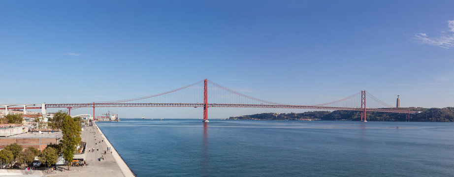 Lisbon, Portugal - October 31, 2016: The 25 de Abril bridge spanning over the Tagus River seen from the Belem District. On the right it’s seen the famous the Cristo-Rei Sanctuary.