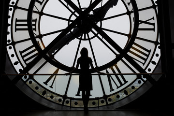 Woman silhouette standing in front of large clock