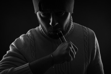 Men with beard vaping on black background in hat