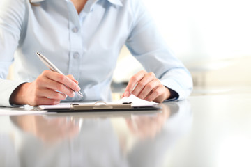 woman hands writing on clipboard with a pen, isolated on desk - obrazy, fototapety, plakaty
