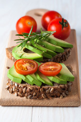 Avocado toast, cherry tomato on wooden background. Breakfast with toast avocado, vegetarian food, healthy diet concept.