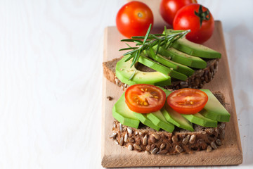 Avocado toast, cherry tomato on wooden background. Breakfast with toast avocado, vegetarian food, healthy diet concept.
