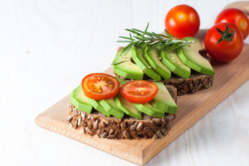 Avocado toast, cherry tomato on wooden background. Breakfast with toast avocado, vegetarian food, healthy diet concept.