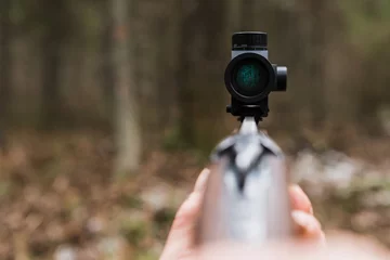 Poster Hunting rifle sight, close-up. Optical sight. A red dot. A man holding a gun. © scharfsinn86