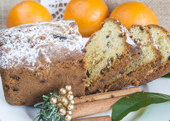Christmas composition with a sliced cake with raisins and glass of tea on a white dish