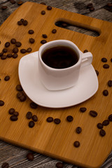 Small cup of coffee, roasted coffee beans on wooden background