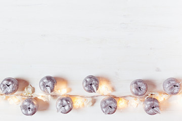 Christmas silver apples decoration and lights burning  on a white wooden background. Xmas background.
