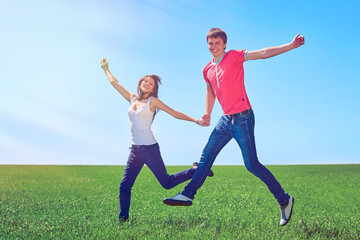 Fototapeta na wymiar Happy couple jumping in green field
