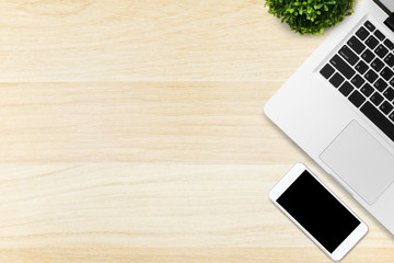 Wood office desk table with laptop and smartphone. Top view with copy space, flat lay.