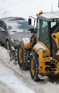 Tractor shoveling snow on the street.