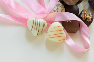 Schokoladenpralinen in Herzform mit rosa Band