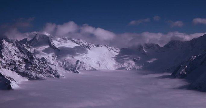 Zillertal, Tirol, Austria - peaks of snowy mountains and valley in the alps above the clouds at a sunny day - Timelapse with zoom out 