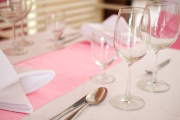 Glasses, forks, knives, plates on a table in restaurant