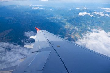 Fototapeta na wymiar Wing of airplane with mountain and foggy from window view