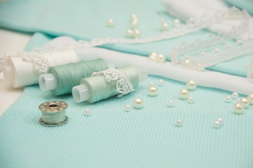 the thread, the beads, the lace are on the turquoise fabric