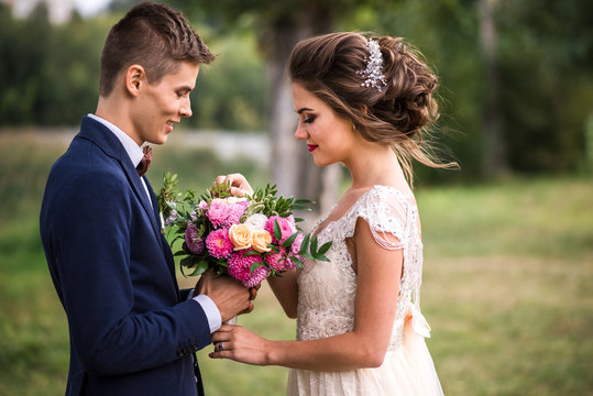 Beautiful young bride and groom holding wedding bouquet. Summertime
