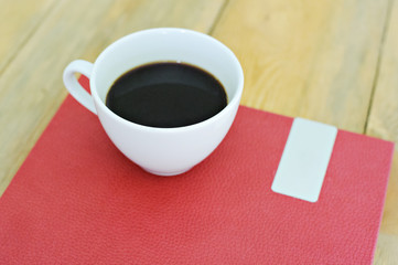 Fototapeta na wymiar White coffee Cup and red book on a wooden background.