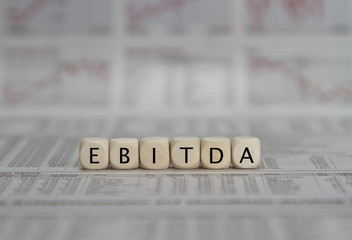 EBITDA word built with letter cubes on newspaper background