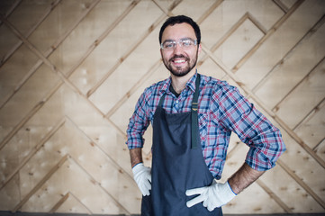 Young male carpenter wearing gloves and glasses with hands on hips