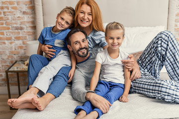 Happy family lying down on bed at home