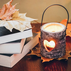 Books and candle holder with autumn leaves