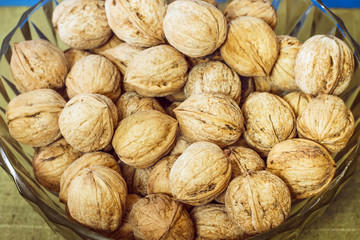 Walnuts in a glass plate on  blue background