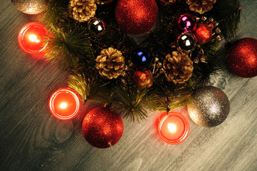 Obraz na płótnie Canvas Christmas arrangement. Fir wreath, Christmas balls, burning candle. Photos shot in a dark key. Photo toned. Soft focus.