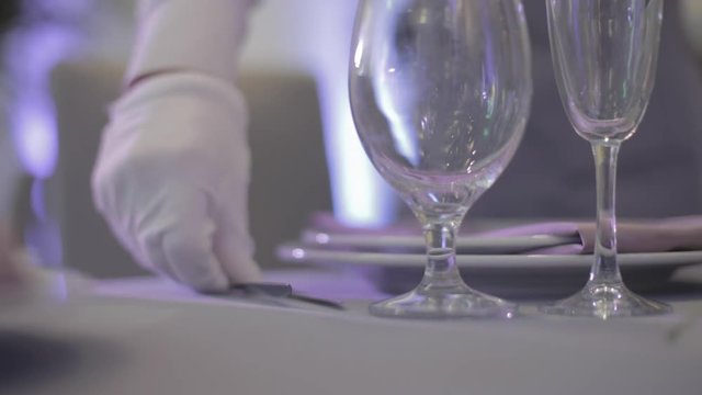 the waiter displays forks on a holiday table, white gloves closeup