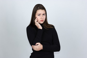 Portrait of a pretty woman having toothache  standing over gray background