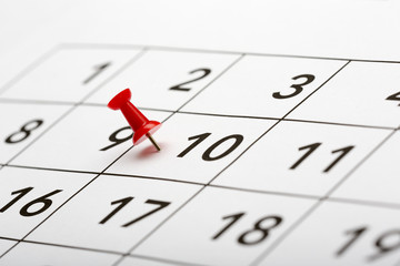 Pin on the date number 10. The tenth day of the month is marked with a red thumbtack. Focus point...