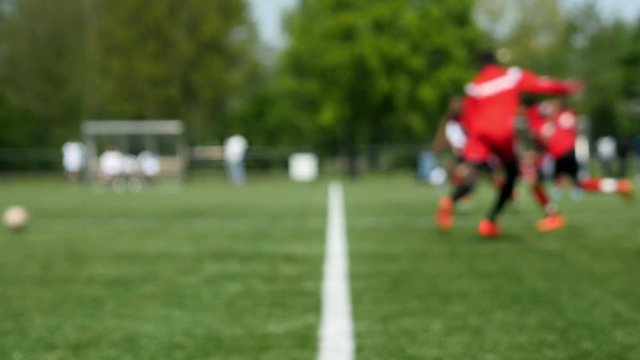 Defocused football match for teenagers, shot from the middle line. Sunny day. Exterior.