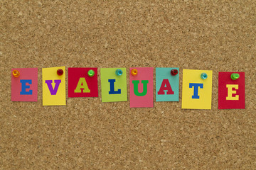 Evaluate word written on colorful sticky notes pinned on cork board.