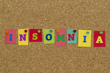 Insomnia word written on colorful sticky notes pinned on cork board.