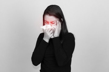 Portrait of a pretty woman in turtleneck sweaterand  having flu. girl blowing nose standing over gray background and black and white with red accent