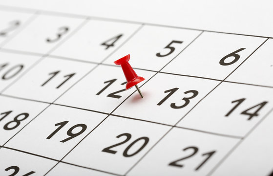 Pin on the date number 13. The thirteenth day of the month is marked with a red thumbtack. Usually referred as friday the thirteenth. Focus point on the red pin.