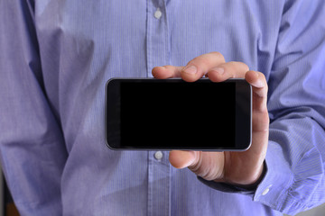 Young man in a blue shirt is holding a phone with the black scre