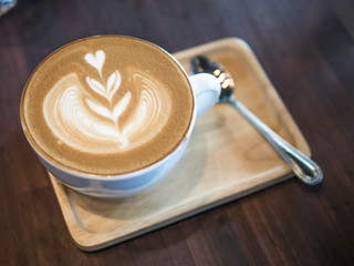 Hot coffee large cappuccino cup with silver spoon on the wooden tray and dark table