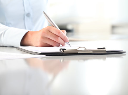 woman hands writing on clipboard with a pen, isolated on desk