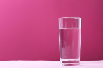 Glass with water on pink background