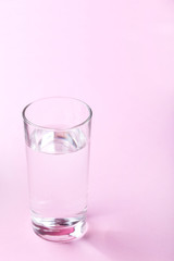 Glass with water on pink background