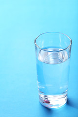 Glass with water on blue background