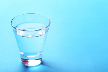 Glass with water on blue background