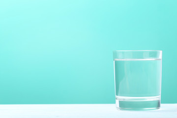 Glass with water on mint background