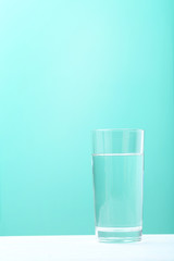 Glass with water on mint background