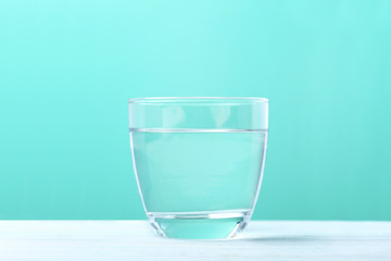 Glass with water on mint background