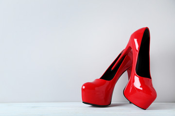 Pair of red women's high-heeled shoes on wooden table